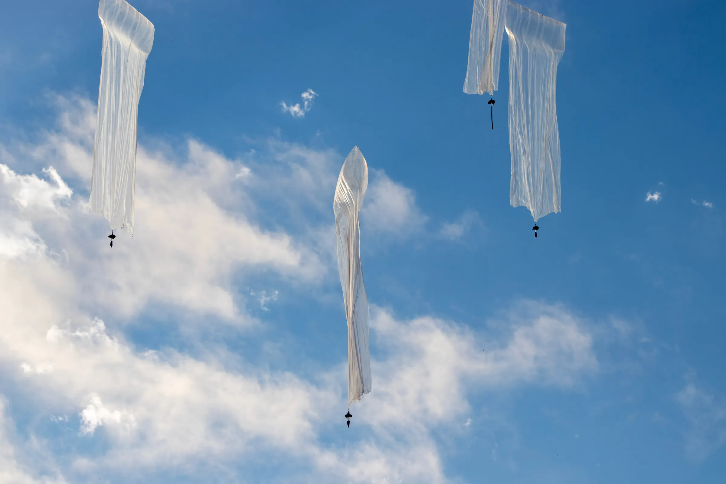 Multiple WindBorne Global Sounding Balloons ascending through a blue sky